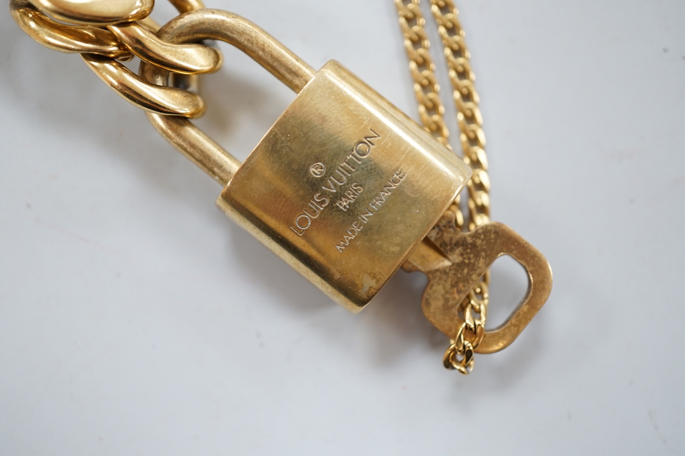 A Louis Vuitton gilt metal key and padlock pendant, 36mm, on a Boutique Secondlife of London, curb link chain, chain 40cm.